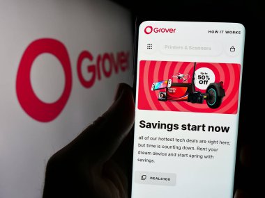 Stuttgart, Almanya - 03-28-2024: Alman tüketici elektroniği kiralama şirketi Grover 'ın internet sayfası ile logo önünde cep telefonu tutan kişi. Telefon ekranının merkezine odaklan.