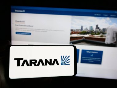 Stuttgart, Germany - 03-28-2024: Person holding smartphone with logo of US telecommunications company Tarana Wireless Inc. in front of website. Focus on phone display. clipart