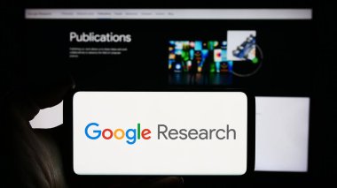 Stuttgart, Almanya - 04-02-2024: İş sayfası önünde ABD 'li teknoloji şirketi Google Research' ün logosuyla cep telefonu tutan kişi. Telefon ekranına odaklan.