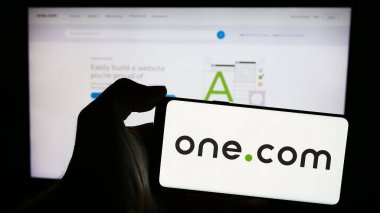 Stuttgart, Almanya - 04-02-2024: İnternet sunuculuğu şirketi One.com Group 'un logosunun bulunduğu cep telefonu sahibi iş sayfası önünde. Telefon ekranına odaklan.