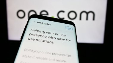 Stuttgart, Almanya - 04-02-2024: İnternet sunucu şirketi One.com Group 'un web sitesi ile birlikte iş logosu önünde akıllı telefon. Telefon ekranının sol üst kısmına odaklan.
