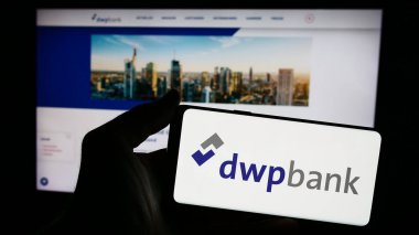 Stuttgart, Germany - 04-02-2024: Person holding smartphone with logo of company Deutsche WertpapierService Bank AG (dwpbank) in front of website. Focus on phone display. clipart