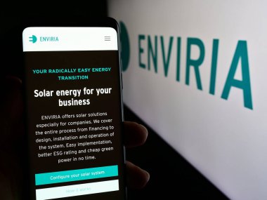 Stuttgart, Almanya - 04-02-2024: Alman güneş enerjisi şirketi ENVIRIA Energy Holding GmbH 'in web sayfası ile cep telefonu tutan kişi logonun önünde. Telefon ekranının merkezine odaklan.