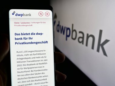 Stuttgart, Germany - 04-02-2024: Person holding cellphone with web page of company Deutsche WertpapierService Bank AG (dwpbank) in front of logo. Focus on center of phone display. clipart