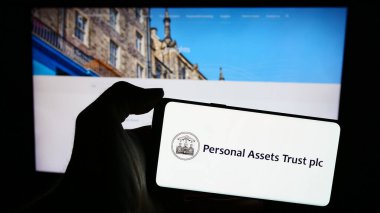 Stuttgart, Almanya - 04-04-2024: İngiliz yatırım şirketi Personel Varlıkları Tröstü logosunun bulunduğu cep telefonu web sayfasının önünde duruyor. Telefon ekranına odaklan.