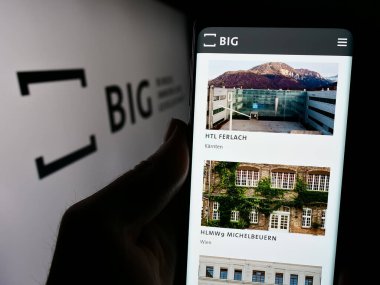 Stuttgart, Almanya - 04-05-2024: Bundesimmobiliengesellschaft m.b.H. şirketinin internet sayfası ile cep telefonu tutan kişi Logonun önündeydi. Telefon ekranının merkezine odaklan.