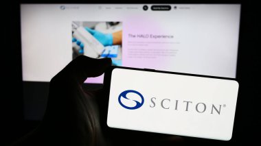 Stuttgart, Almanya - 04-05-2024: Amerikan tıbbi cihaz şirketi Sciton Inc. 'in logosunun bulunduğu cep telefonu sahibi kişi iş sayfasının önünde. Telefon ekranına odaklan.