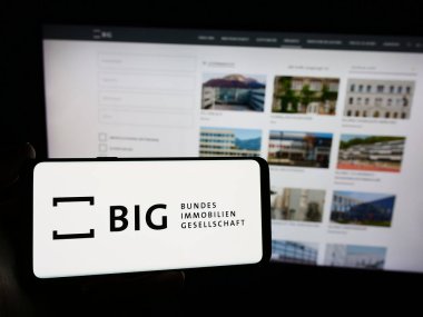 Stuttgart, Almanya - 04-05-2024: Bundesimmobiliengeselschaft m.b.H. şirketinin logosuna sahip kişi - Web sitesinin önünde. Telefon ekranına odaklan.