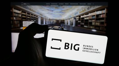 Stuttgart, Almanya - 04-05-2024: Avusturyalı Bundesimmobiliengeselschaft m.b.H. logosuna sahip cep telefonu sahibi kişi Web sayfasının önündeyim. Telefon ekranına odaklan.