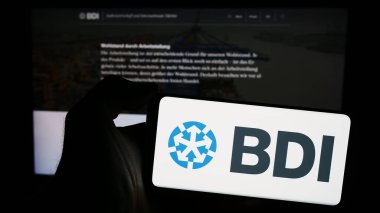 Stuttgart, Almanya - 04-07-2024: Bundesverband der Deutschen Industrie E.V. logosuna sahip cep telefonu sahibi kişi (BDI) Web sayfasının önünde. Telefon ekranına odaklan.
