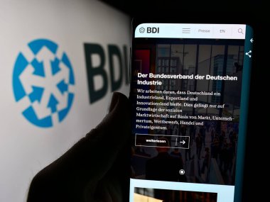 Stuttgart, Almanya - 04-07-2024: Bundesverband der Deutschen Industrie E.V. web sayfası ile cep telefonu tutan kişi (BDI) Logonun önünde. Telefon ekranının merkezine odaklan.