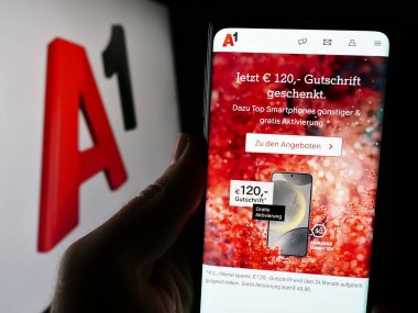 Stuttgart, Almanya - 04-07-2024: Telekom Austria AG (A1) adlı telekomünikasyon şirketinin web sayfası logonun önünde bulunan kişi. Telefon ekranının merkezine odaklan.