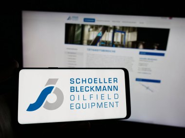 Stuttgart, Almanya - 04-07-2024: Web sitesi önünde Schoeller-Bleckmann Oilfield Equthe AG şirketinin logosuna sahip akıllı telefon sahibi kişi. Telefon ekranına odaklan.