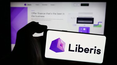 Stuttgart, Almanya - 04-07-2024: İngiliz finans hizmetleri şirketi Liberis Ltd. 'nin logosuyla cep telefonu tutan kişi iş sayfasının önünde. Telefon ekranına odaklan.