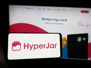 Stuttgart, Almanya - 04-07-2024: İngiliz finans teknoloji şirketi HyperJar Limited 'in logosuna sahip akıllı telefon sahibi kişi web sitesi önünde. Telefon ekranına odaklan.