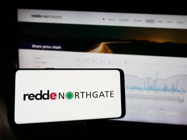 Stuttgart, Almanya - 04-07-2024: İngiliz araç kiralama şirketi Redde Northgate plc 'nin logosuna sahip cep telefonu sahibi kişi iş sayfasının önünde. Telefon ekranına odaklan.