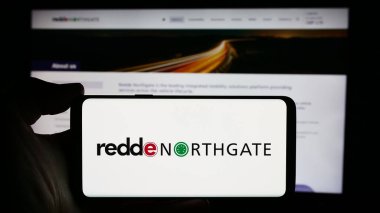 Stuttgart, Almanya - 04-07-2024: İngiliz araç kiralama şirketi Redde Northgate plc 'nin logosuna sahip cep telefonu sahibi kişi iş sayfasının önünde. Telefon ekranına odaklan.