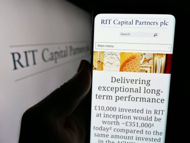 Stuttgart, Almanya - 04-07-2024: İngiliz yatırım şirketi RIT Capital Partners 'ın logolu web sitesiyle cep telefonu tutan kişi. Telefon ekranının merkezine odaklan.