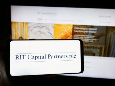 Stuttgart, Almanya - 04-07-2024: İngiliz yatırım şirketi RIT Capital Partners plc 'nin logosuna sahip akıllı telefon sahibi kişi web sitesinin önünde. Telefon ekranına odaklan.