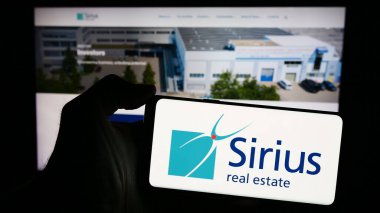 Stuttgart, Almanya - 04-08-2024: Ticari emlak şirketi Sirius Real Estate Limited 'in logosuna sahip akıllı telefon sahibi kişi web sitesinin önünde. Telefon ekranına odaklan.