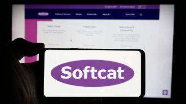 Stuttgart, Germany - 04-08-2024: Person holding cellphone with logo of British information technology company Softcat plc in front of business webpage. Focus on phone display. clipart