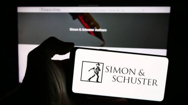 Stuttgart, Germany - 04-08-2024: Person holding mobile phone with logo of American publishing company Simon and Schuster LLC in front of business web page. Focus on phone display. clipart