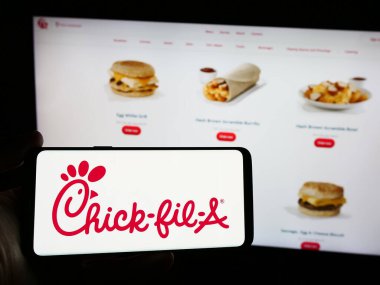 Stuttgart, Almanya - 04-08-2024: İnternet sitesi önünde üzerinde ABD 'li fast food restoran şirketi Chick-fil-A Inc.' in logosu bulunan kişi. Telefon ekranına odaklan.