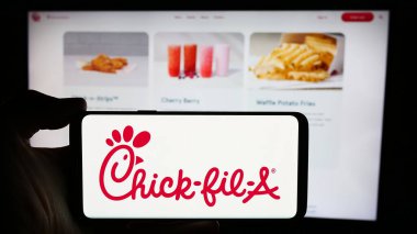 Stuttgart, Almanya - 04-08-2024: İnternet sayfasının önünde Amerikan fast food restoran şirketi Chick-fil-A Inc. 'in logosuna sahip cep telefonu sahibi kişi. Telefon ekranına odaklan.