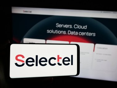 Stuttgart, Almanya - 04-08-2024: Rus bulut altyapı şirketi Selectel Ltd. 'nin logosuyla cep telefonu tutan kişi iş sayfasının önünde. Telefon ekranına odaklan.