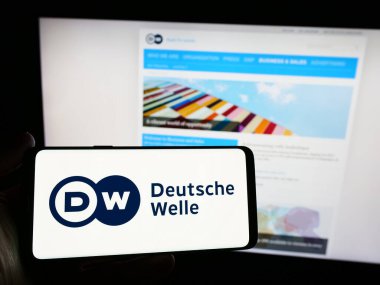 Stuttgart, Almanya - 04-10-2024: İnternet sitesi önünde Alman devlet yayın kuruluşu Deutsche Welle 'in (DW) logosuna sahip kişi. Telefon ekranına odaklan.