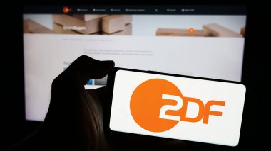 Stuttgart, Almanya - 04-10-2024: İnternet sayfası önünde Zweites Deutsches Fernsehen (ZDF) logosu bulunan cep telefonu sahibi kişi. Telefon ekranına odaklan.