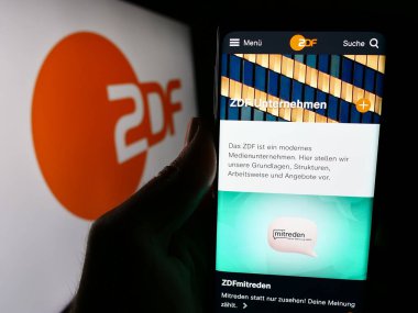 Stuttgart, Almanya - 04-10-2024: Televizyon kanalı Zweites Deutsches Fernsehen 'in (ZDF) logolu web sayfası ile akıllı telefon tutan kişi. Telefon ekranının merkezine odaklan.