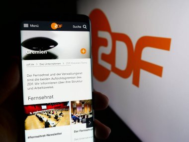 Stuttgart, Almanya - 04-10-2024: Cep telefonunda televizyon kanalı Zweites Deutsches Fernsehen 'in (ZDF) logolu web sayfası bulunan kişi. Telefon ekranının merkezine odaklan.