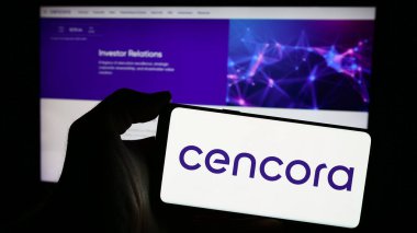 Stuttgart, Almanya - 04-12-2024: İnternet sitesi önünde ABD 'li toptan ilaç şirketi Cencora Inc.' in logosuna sahip kişi. Telefon ekranına odaklan.