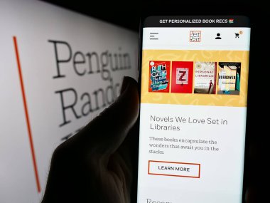 Stuttgart, Almanya - 04-12-2024: ABD 'li yayınevi Penguen Random House' un internet sayfası ile iş logosu önünde cep telefonu tutan kişi. Telefon ekranının merkezine odaklan.