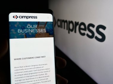 Stuttgart, Almanya - 04-12-2024: Kitle özelleştirme şirketi Cimpress plc 'nin web sayfası ile birlikte logo önünde akıllı telefon tutan kişi. Telefon ekranının merkezine odaklan.