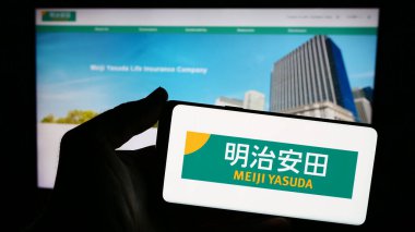 Stuttgart, Almanya - 04-12-2024: Japon iş dünyası Meiji Yasuda Hayat Sigortası Şirketi 'nin logosuna sahip akıllı telefon sahibi kişi web sitesi önünde. Telefon ekranına odaklan.