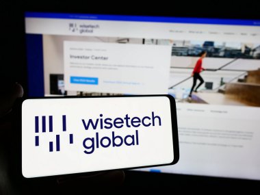 Stuttgart, Almanya - 04-12-2024: Avustralyalı yazılım şirketi WiseTech Global Limited 'in logosuna sahip cep telefonu sahibi kişi web sayfasının önünde. Telefon ekranına odaklan.