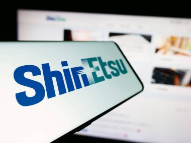 Stuttgart, Germany - 04-13-2024: Cellphone with logo of Japanese chemicals company Shin-Etsu Chemical Co. Ltd. in front of business website. Focus on left of phone display. clipart