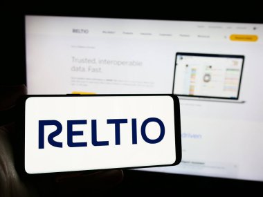 Stuttgart, Almanya - 04-13-2024: Amerikan yazılım şirketi Reltio Inc. 'in logosunu taşıyan cep telefonu sahibi kişi iş sayfasının önünde. Telefon ekranına odaklan.