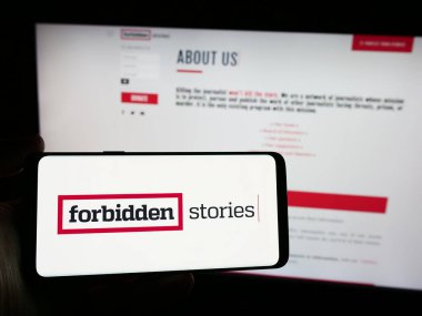 Stuttgart, Almanya - 04-13-2024: Araştırmacı gazetecilik örgütü Yasak Hikayeler 'in logosuna sahip akıllı telefon sahibi kişi web sitesi önünde. Telefon ekranına odaklan.