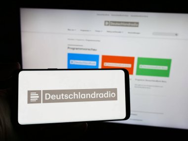 Stuttgart, Almanya - 04-13-2024: İnternet sitesi önünde Alman devlet radyo kanalı Deutschlandradio 'nun logosuna sahip kişi. Telefon ekranına odaklan.