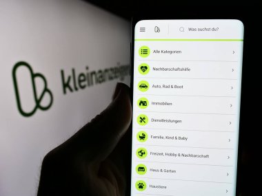 Stuttgart, Almanya - 04-13-2024: Elinde Almanca sınıflandırılmış platform şirketi kleinanzeigen.de GmbH 'nin logolu web sayfası bulunan kişi. Telefon ekranının merkezine odaklan.