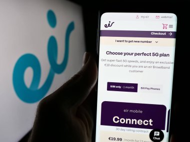 Stuttgart, Almanya - 04-13-2024: İrlandalı telekomünikasyon şirketi Eircom Limited 'in (Eir) logonun önünde cep telefonu tutan kişi. Telefon ekranının merkezine odaklan.