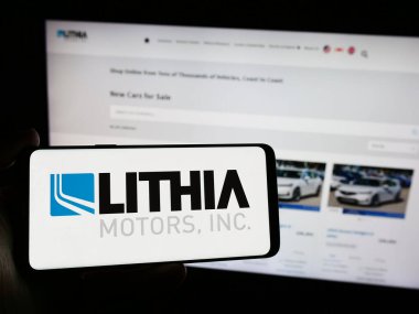 Stuttgart, Almanya - 04-13-2024: Web sitesi önünde ABD 'li otomobil bayii şirketi Lithia Motors Inc.' nin logosuna sahip kişi. Telefon ekranına odaklan.