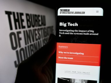 Stuttgart, Almanya - 04-13-2024: Organizasyon web sitesi The Bureau of Investigative Journalism (TBIJ) ile logolu cep telefonu tutan kişi. Telefon ekranının merkezine odaklan.