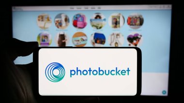 Stuttgart, Almanya - 04-15-2024: İş sayfası önünde ABD imaj sunucu şirketi Photobucket.com Inc. 'nin logosuyla cep telefonu tutan kişi. Telefon ekranına odaklan.