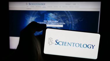 Stuttgart, Almanya - 04-15-2024: İnternet sayfası önünde dini örgüt Scientology logosu bulunan cep telefonu sahibi kişi. Telefon ekranına odaklan.