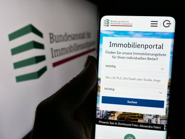 Stuttgart, Almanya - 04-15-2024: Alman Bundesanstalt fuer Immobilienaufgaben (BImA) sitesinin logolu cep telefonu sahibi kişi. Telefon ekranının merkezine odaklan.