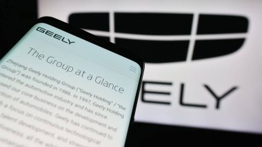 Stuttgart, Almanya - 11-16-2023: Çinli otomobil üreticisi Zhejiang Geely Holding Group 'un web sitesi ile birlikte iş logosu önünde cep telefonu. Telefon ekranının sol üst kısmına odaklan.